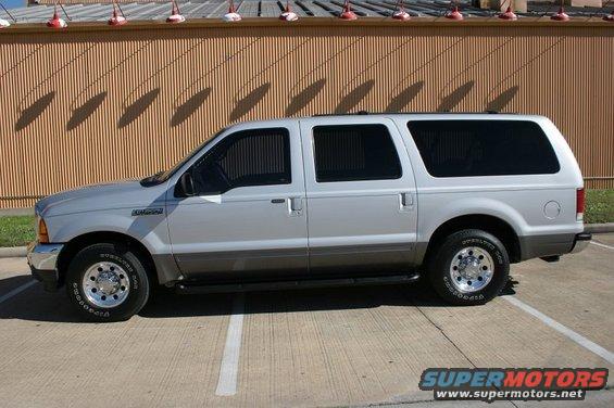Silver Ford Excursion SUV parked on pavement, side view
