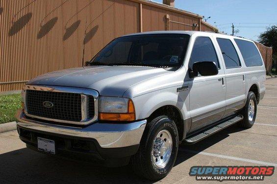 Silver Ford Excursion parked outside a building