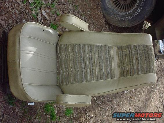 Vehicle seat with tan vinyl and striped fabric inserts. Tire visible in background
