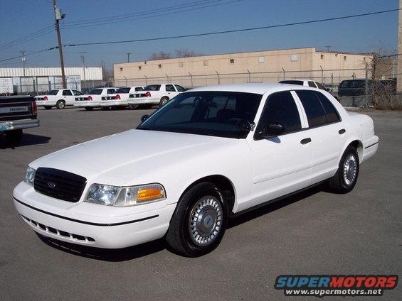 White 1998 Ford Crown Victoria, front 3/4 view, parked in lot with other white sedans