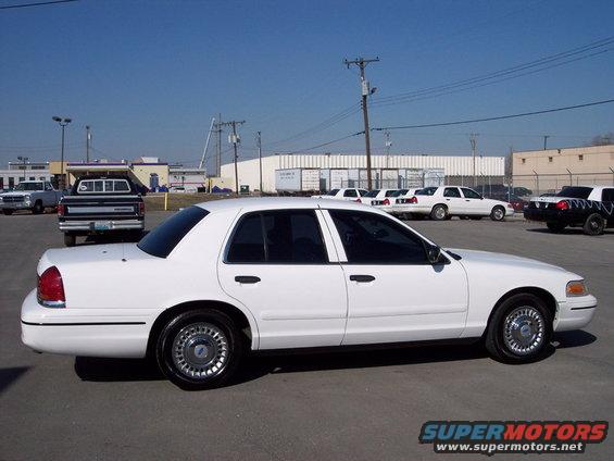 White 1999 Ford Crown Victoria parked in lot with other cars and trucks