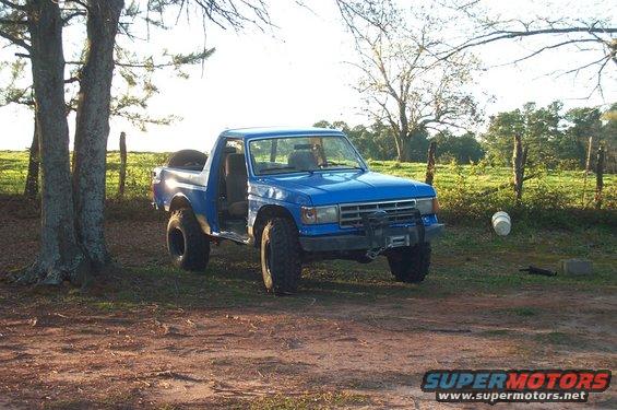 Blue 1987 Ford Bronco with winch and off-road tires parked outdoors
