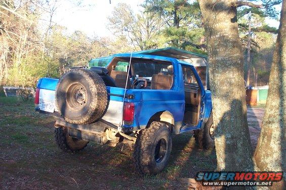 Blue Ford Bronco with a spare tire mounted on the rear, seen from the back