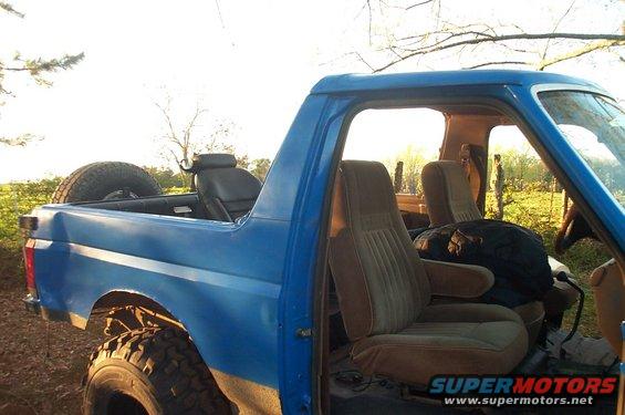 Blue Ford Bronco interior with brown seats and spare tire in the rear