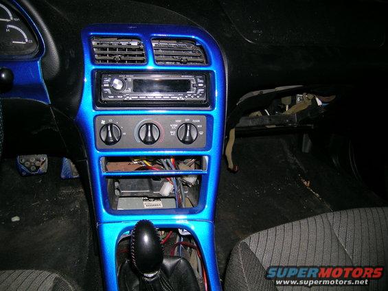 Car interior dashboard with custom blue paint, aftermarket stereo, and exposed wiring