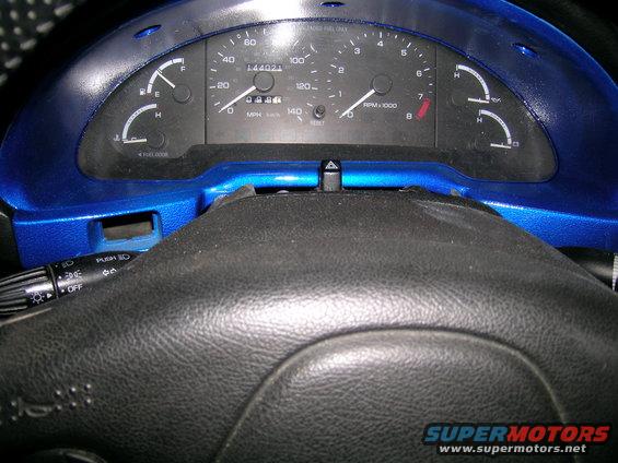 Blue dashboard with speedometer, tachometer, fuel gauge, and odometer. Steering wheel is black