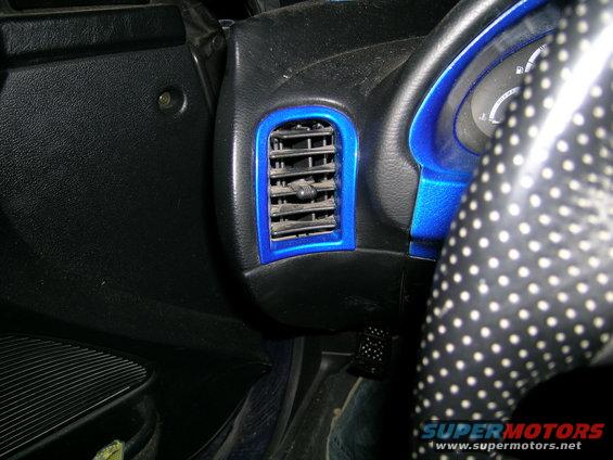 Blue-trimmed air vent and part of a polka-dot steering wheel inside a car