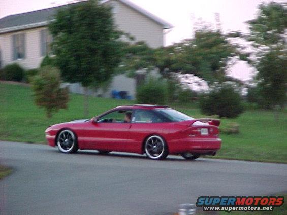 Red 1994 Ford Probe driving on a road, 3q-front view