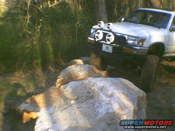 White SUV with off-road lights navigating large rocks on a trail