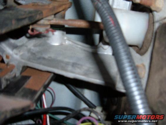 Close-up of vehicle clutch pedal assembly with wiring and metal components