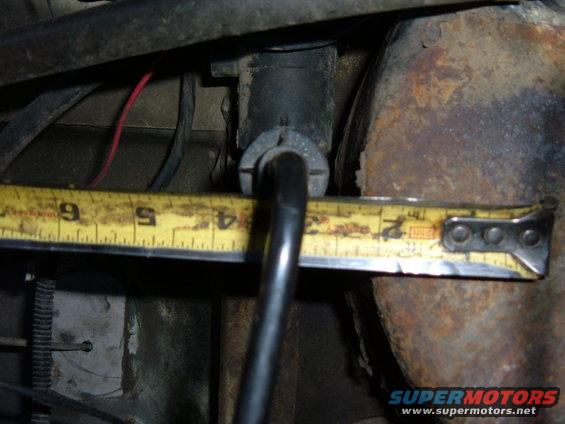 Close-up of a measuring tape across some rusty vehicle parts and wires