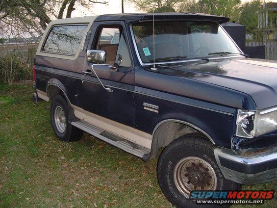 1989 Ford Bronco, dark blue with tan two-tone trim, parked on grass