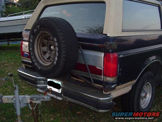 Rear view of a 1989 Ford Bronco with a spare tire mounted on the back. It's hitched to a trailer