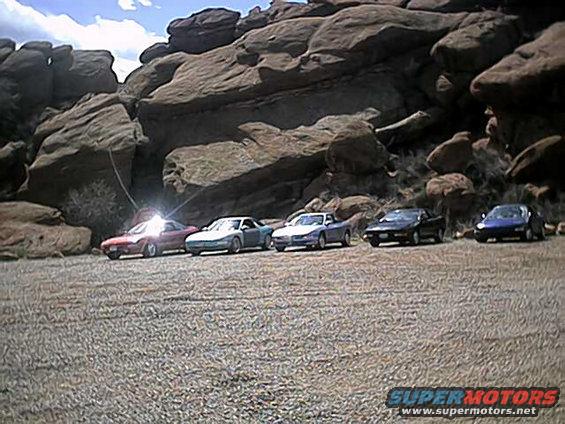 five sports cars parked in front of large rock formations