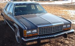 Dark sedan, 3q-front view. Likely 1980s model