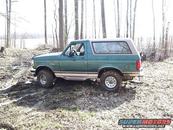 Green 1996 Ford Bronco side view, stuck in mud