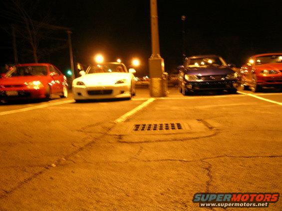 Four cars parked at night, front view. Red, white, blue, and orange cars are visible