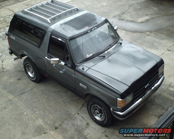Gray 1987 Ford Bronco parked on concrete. It has a roof rack and 4x4 badging