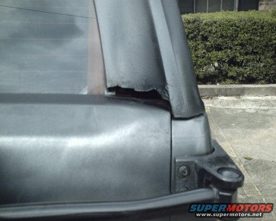 Close-up of damaged rear window frame on a vehicle. Supermotors.net logo visible