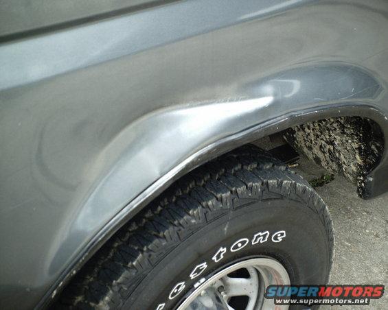 Gray 1987 Ford Bronco fender with a dent above the wheel well and a Firestone tire