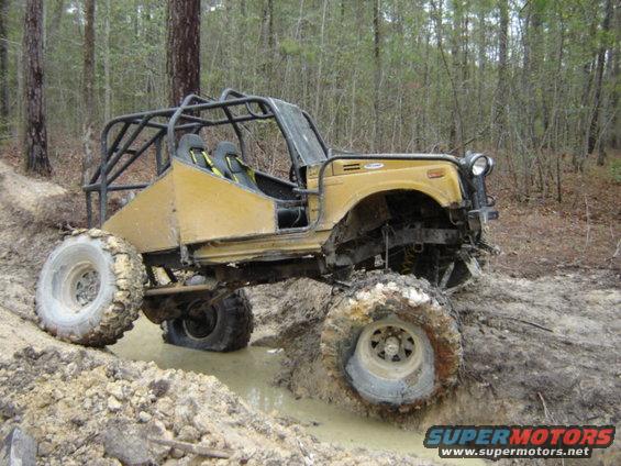 Yellow off-road buggy with roll cage stuck in mud on a trail