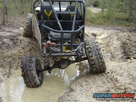Buggy with roll cage stuck in mud pit, rear view