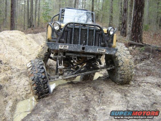 Off-road vehicle with large tires navigating a muddy ditch