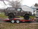1979 Ford Bronco - A camouflaged Ford Bronco is loaded onto a red trailer, ready for transport.