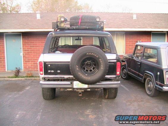 1978 Ford Bronco rear, black hardtop, roof rack, spare tire on tailgate, parked next to another SUV