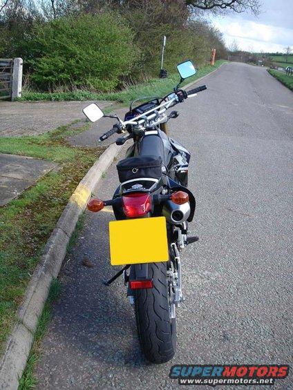 Black motorcycle with yellow license plate parked on asphalt road