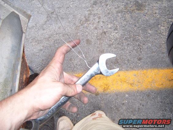 Hand holding a wrench with wire