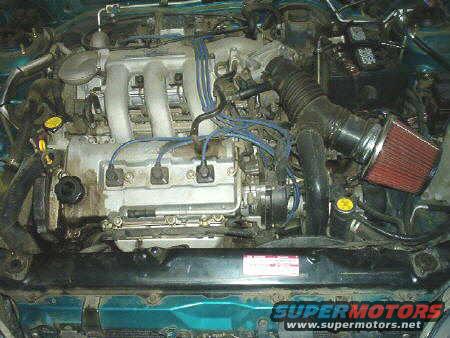 1994 Mazda MX-3 engine bay with aftermarket air filter, blue spark plug wires, and visible radiator