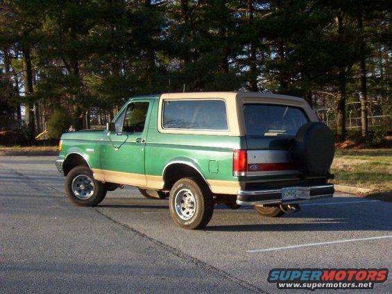 Green and tan Ford Bronco, rear 3/4 view, with a spare tire mounted on the tailgate