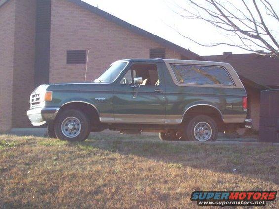Green 1989 Ford Bronco parked on a grassy incline