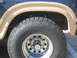 1986 Ford Bronco - Close-up of a tire and wheel assembly on a vehicle, with visible fender flare and wheel well details.