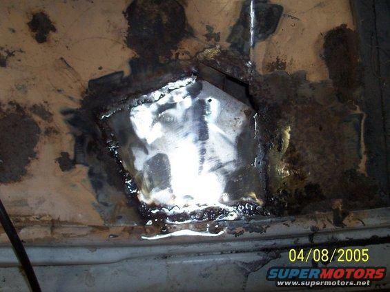 Close-up of rusted metal panel with a patch welded over a hole
