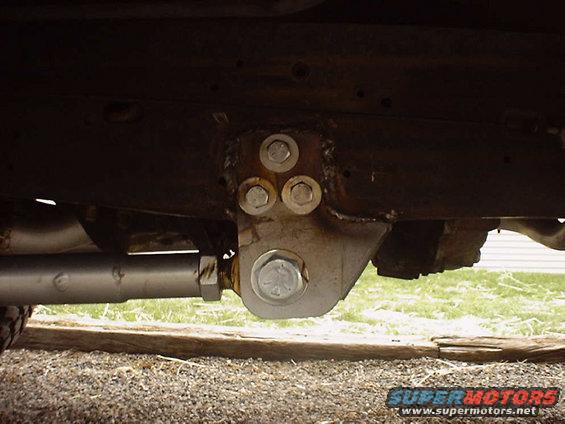 Close-up of a suspension component with multiple bolts attached to a frame