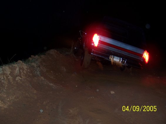 Truck with illuminated taillights driving on a dirt embankment at night