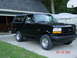 1996 Ford Bronco - A black 1996 Ford Bronco is parked in a driveway next to a garage and a covered boat.
