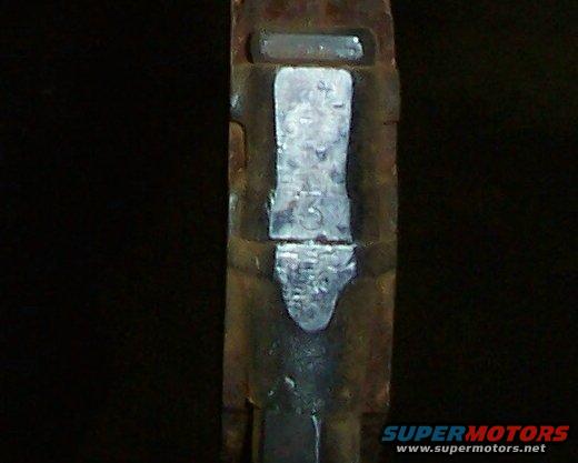 Close-up of a metal part with stamped numbers, possibly a VIN or part number