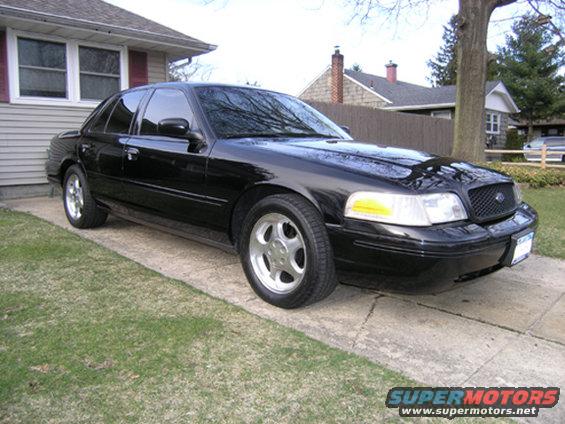 Black sedan parked on a driveway in front of a house