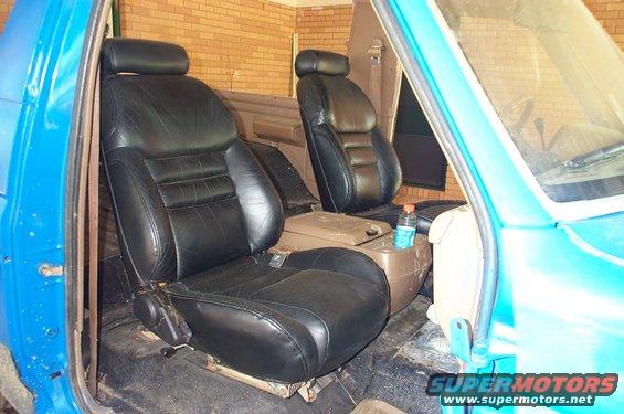 Interior of a blue SUV showing two black leather bucket seats and a center console with a water bottle