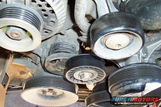 Engine pulleys and belts, close-up view. Some pulleys are ribbed, others are smooth