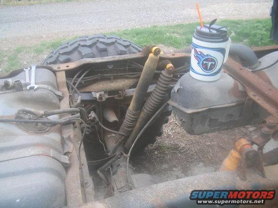 Truck frame showing fuel tank, shocks, and a tire. A mug with a Titans logo sits on top of a fuel tank
