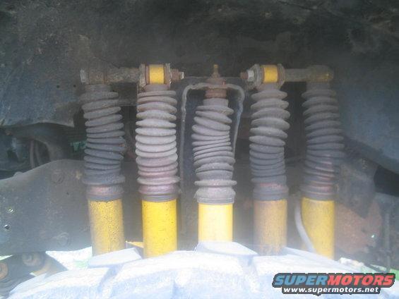 Five yellow shock absorbers with gray bellows, viewed from below