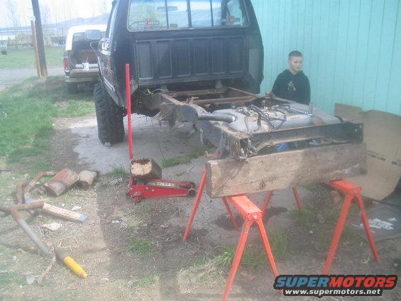 Truck bed removed, frame and fuel tank on sawhorses, another truck in background