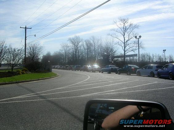 Cars parked in a lot, seen from a side mirror. A watermark says SUPERMOTORS.NET