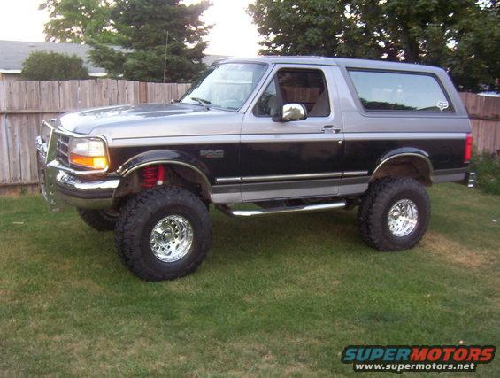 1994 Ford Bronco with aftermarket wheels and lift kit parked on grass
