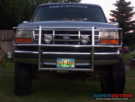 Front view of a dark gray Ford truck with a chrome bull bar and aftermarket lights. License plate reads 427 ABP