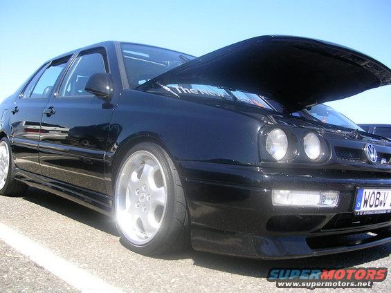 Black sedan with hood open, custom wheels, and a license plate reading WOB-V